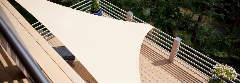 Beigefarbenes Sonnensegel über Holzterrasse